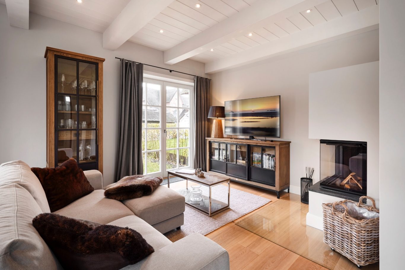 Wohnbereich Moderner Wohnraum mit hellen Wänden, Sofa, TV und Kamin. Große Fenster mit Vorhängen.