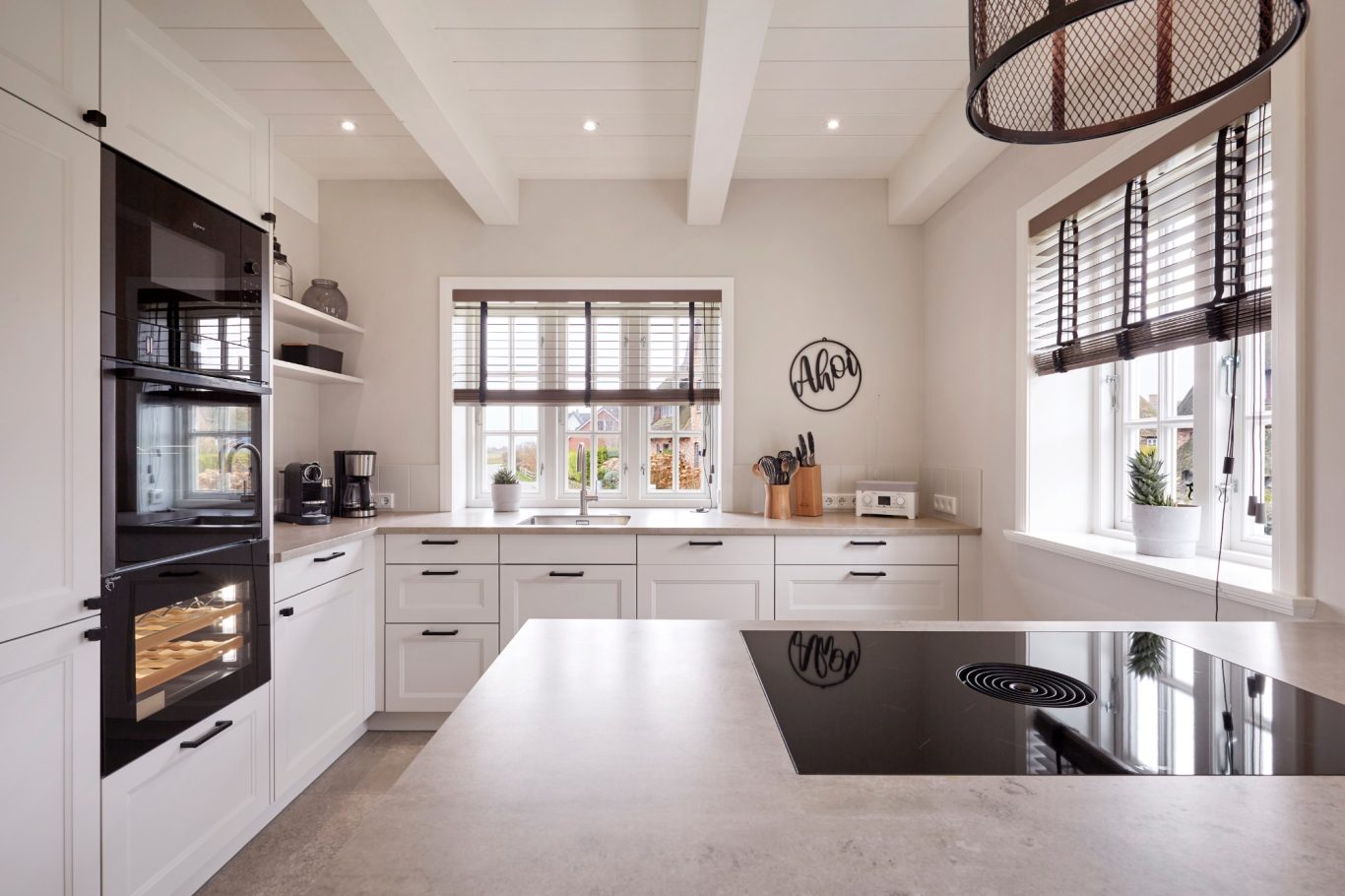 Bora-Kochinsel Moderne Küche mit Kochinsel, hellen Möbeln und großen Fenstern.