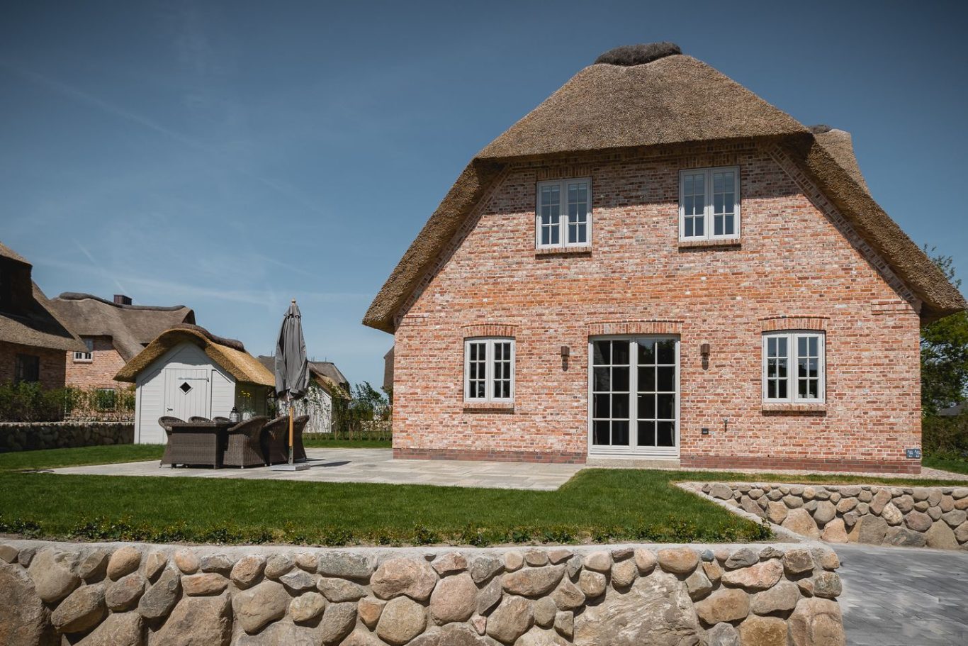 Süd-Terrasse Ferienhaus mit Reetdach und Terrasse in ländlicher Umgebung.