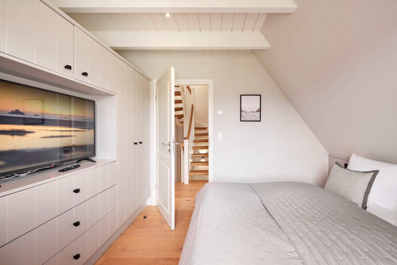 Zweites Schlafzimmer Helle Schlafzimmer mit Bett, Fernsehschrank und offener Tür zu den Treppen.