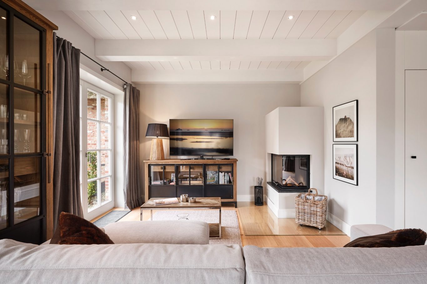 Glaskamin Modern Wohnzimmer mit Fernseher, Kamin, Holztisch und gemütlicher Dekoration.