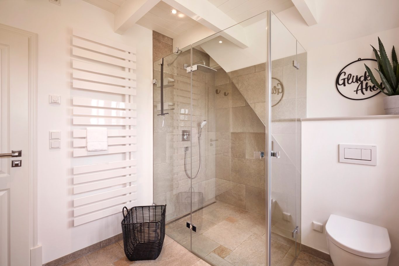 Rainshower-Dusche Moderne Badezimmer mit Dusche, WC und Pflanzen. Helle Fliesen, Glasabtrennung, Wäschekorb.